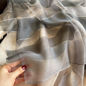 Macro shot of lightweight grey striped silk blend scarf fabric with shimmering metallic threads