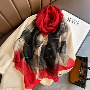 Detail of color-block plaid scarf with silver metallic thread coiled as a rose