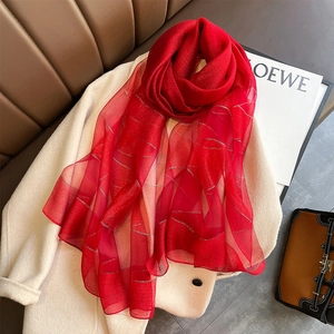 Close-up of red scarf with silver wave patterns layered on a beige wool coat texture