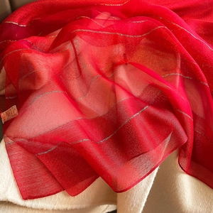 Detailed close-up of red semi-transparent scarf featuring subtle metallic gold stripes