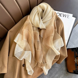 Champagne and coffee gradient silk scarf styled with a camel wool coat on a leather sofa
