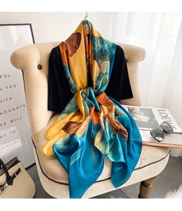 Detail of satin silk scarf with artistic ginkgo leaf print in blue and yellow tones
