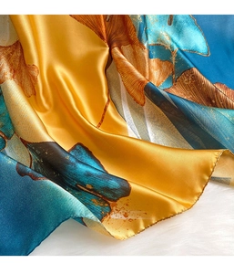 Macro detail of faux silk scarf featuring golden ginkgo leaves and smooth satin texture