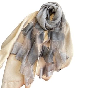 Elegant grey silk blend scarf with geometric block patterns on wool coat background