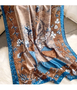 Detail van zijdeachtige bloemensjaal met blauw-bruin bamboemotief op zachte pluche achtergrond