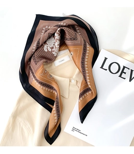 Detailed close-up of paisley silk scarf with contrast patterns on a beige shirt