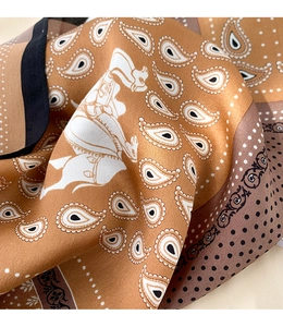 Detailed close-up of silk scarf showing equestrian horse print and paisley pattern