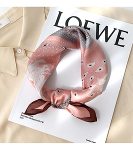 Detail of silk scarf with pink and grey paisley pattern tied in a knot on a shirt