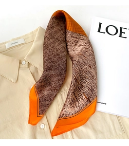 Détail d'un foulard en soie élégant avec motifs géométriques et bordure orange vif