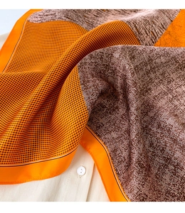 Détail d'un foulard en soie montrant des motifs pied-de-poule et chevrons orange et marron