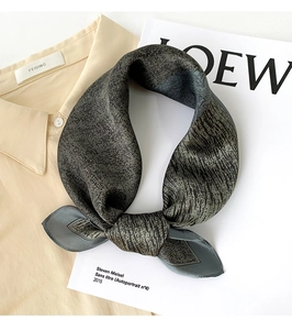 Détail d'un foulard en soie vert foncé montrant la texture à chevrons sur une chemise