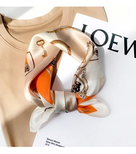 Detail of silk square scarf featuring vintage gold chain and key patterns on beige fabric