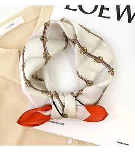 Detail of silk square scarf with belt and chain print tied on a shirt collar