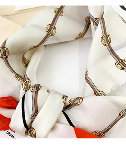 Detailed close-up showing the smooth satin texture and elegant chain pattern of this silk scarf