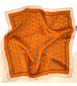 Detailed view of the orange silk scarf showing classic link patterns and soft textures