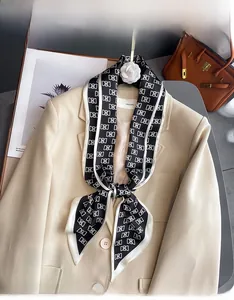Vue détaillée d'un foulard en soie noir et blanc à monogramme sur un costume beige