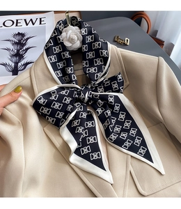 Détail du foulard en soie noir et blanc à motif géométrique porté sur un blazer beige