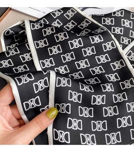 Vue détaillée d'un foulard en soie noir et blanc à motifs de lettres et bordure contrastée