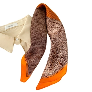 Petit foulard en soie aux motifs géométriques orange et marron sur chemise beige
