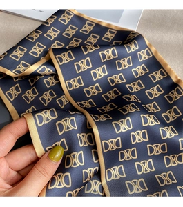 Vue détaillée d'un foulard en soie bleu marine avec motif doré et bords surpiqués