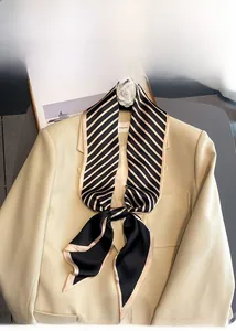 Close-up of striped faux silk scarf tied on a beige blazer collar for a chic look