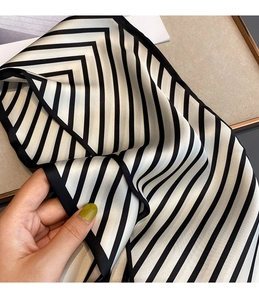 Detail of elegant black and white striped silk scarf with smooth satin texture and black border
