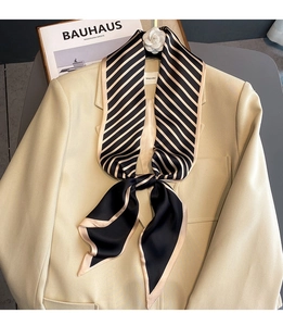 Detail of elegant black and beige striped silk scarf tied around a blazer collar