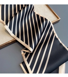 Detail of elegant black and champagne striped satin silk scarf with glossy finish