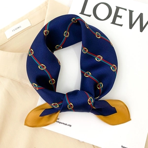 Navy blue silk scarf with red-green stripes and gold horsebit patterns in bow shape