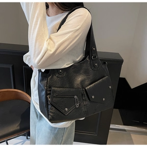 Detail der schwarzen Kunstledertasche mit funktionellen Taschen und Metallnieten