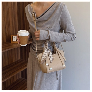 Detail of beige lychee leather bucket bag with houndstooth silk scarf on the handle