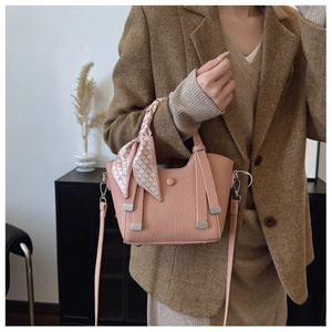 Pink lychee texture bucket bag with silk scarf handle detail worn with a stylish blazer