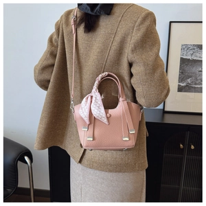 Pink lychee grain bucket bag with plaid scarf and long shoulder strap shown on model
