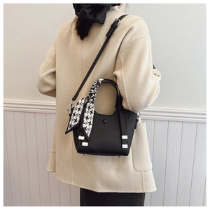 Close-up of black lychee leather bucket bag with houndstooth silk scarf on handle