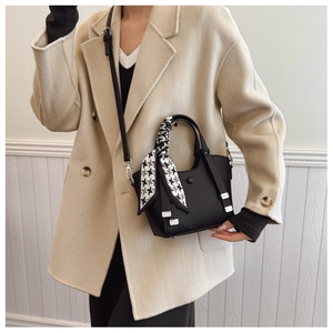 Detail of black lychee grain leather bucket bag with houndstooth silk scarf handle