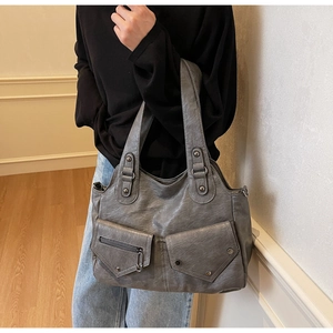 Detail der grauen Vintage-Schultertasche mit Frontklappentaschen und Metallnieten