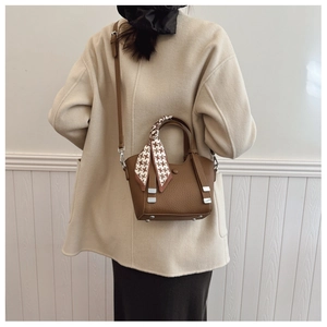 Close-up of brown litchi pattern leather bucket bag with silk scarf detail on handle