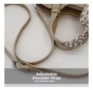 Detail of adjustable leather strap and houndstooth silk scarf on beige bucket bag handle
