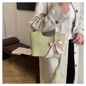 Detail of light green pebbled leather bucket bag with decorative silk scarf and gold hardware