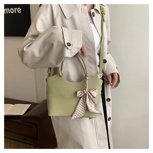 Detail of light green pebbled leather handbag with printed silk scarf and gold hardware