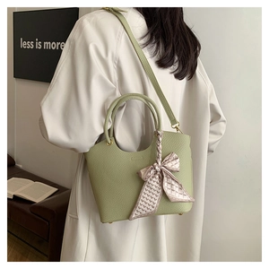 Close-up of light green lychee pattern leather bucket bag with a decorative silk scarf