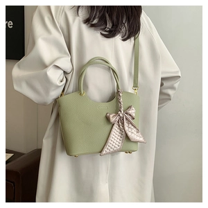 Green bucket bag with lychee texture and decorative silk scarf shown on model