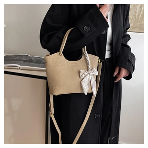 Detail of beige lychee grain bucket bag with silk scarf on a black coat model