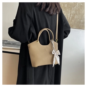 Detail of khaki leather bucket bag with silk scarf accent and golden metal studs