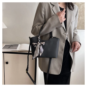 Detail of black lychee grain leather bucket bag with decorative silk scarf on handle