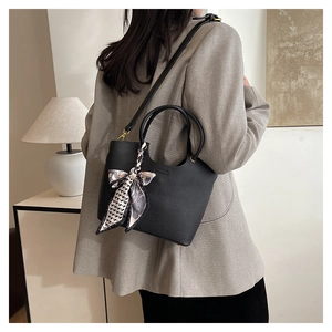 Detailed back view of a black pebbled leather bucket bag with a decorative silk scarf handle