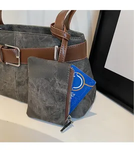 Detail van grijze schoudertas met textuur, lederen riem en afneembare mini-portemonnee