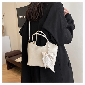 Detailed side view of cream bucket bag with litchi texture and elegant silk scarf handle