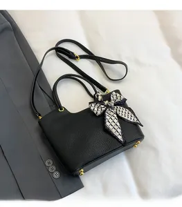 Detail of black lychee grain leather bucket bag with geometric silk scarf and gold studs
