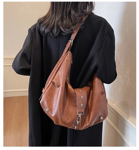 Detail of vintage brown hobo bag showing soft faux leather texture and star rivet accents